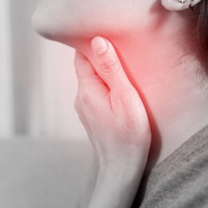 A person holding their throat, with a red glow highlighting the neck area, suggesting pain or discomfort, possibly due to a sore throat or illness.